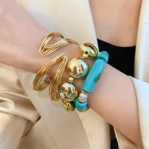 Close-up detail of stylish gold wire cuff and turquoise bead bracelet set on wrist