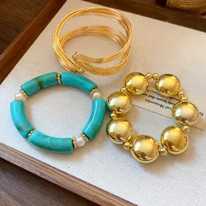 Close-up of three elegant bracelets featuring gold beads, turquoise acrylic, and wire