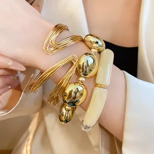 Detailed close-up view of elegant gold metal and cream acrylic bracelet set on model's wrist