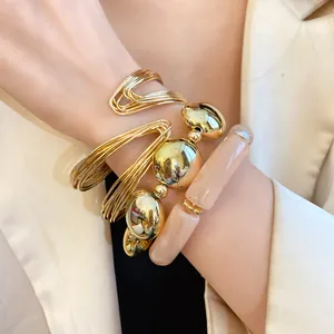Close-up of gold tone metal cuff and acrylic bead stretch bracelets on a wrist.