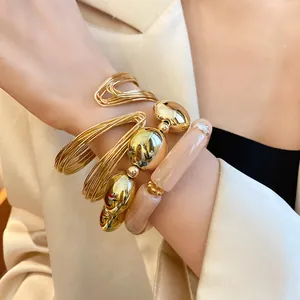 Detailed view of stacked gold wire bangles and beige acrylic bead bracelets