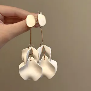 Dettaglio di orecchini pendenti con petali in acrilico e finitura in colore oro