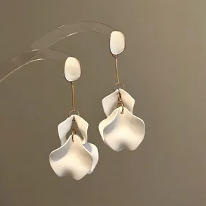 Dettaglio di eleganti orecchini con petali di fiori in acrilico bianco e oro