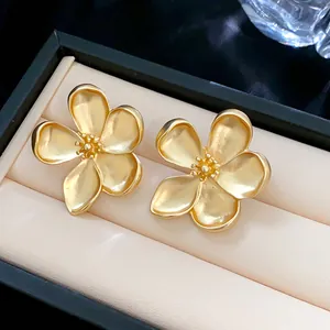 Primer plano de pendientes de flores de cinco pétalos dorados con textura