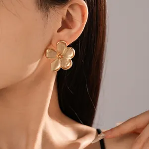 Detalle elegante de un pendiente de flor de cinco pétalos en oro mate en oreja de modelo