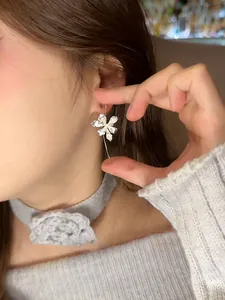 Close-up of elegant silver iris flower drop earrings on an Asian model wearing a choker