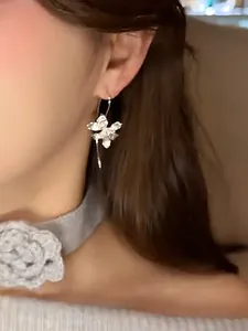 Detailed close-up showing a vintage silver iris flower hook earring worn by a model.