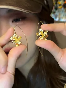Close-up detail of retro gold iris flower earrings with elegant textured petals.