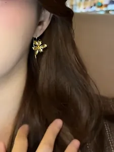 Close-up of elegant vintage gold Iris flower ear hook earrings worn by a model