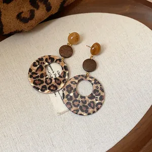 Nahaufnahme von Leopard-Resin- und Holzohrringen in Vintage-Ästhetik für Damen