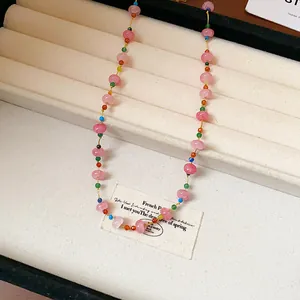 Détail d'un collier de perles en verre rose coloré sur un plateau de présentation