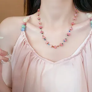 Vue détaillée d'un collier en acier inoxydable avec perles de verre roses sur un mannequin