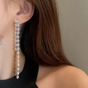 Primo piano di eleganti orecchini lunghi a goccia con nappe in zircone luccicante