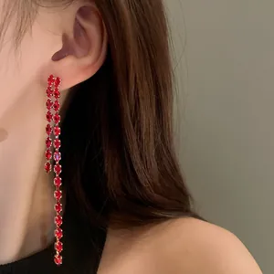 Primo piano di eleganti orecchini a nappa lunga con zirconi rossi scintillanti