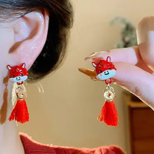 Primo piano di orecchini a forma di cavallo in smalto rosso con nappine festive.