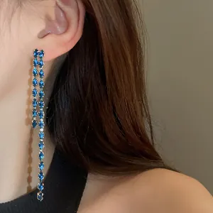 Dettaglio di eleganti orecchini lunghi a nappa con zirconi blu dal taglio marquise su modella