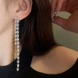 Primo piano di eleganti orecchini a nappa lunga in zircone su un orecchio di modella.