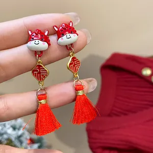 Dettaglio orecchini festivi con nappa a forma di cavallo rosso e ciondoli Fu oro.
