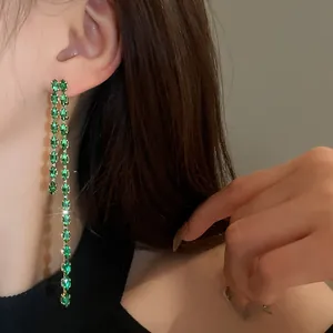 Dettaglio macro di orecchini pendenti in argento con nappe e brillanti zirconi verdi