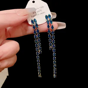 Dettaglio di orecchini a nappa lunga con scintillanti pietre blu marquise