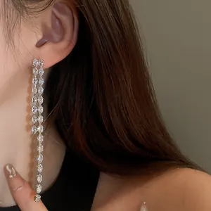 Primo piano di eleganti orecchini lunghi con nappe di zirconi indossati da una modella.