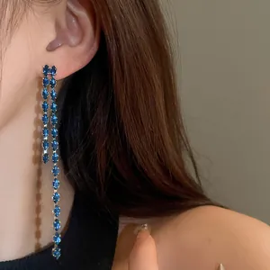 Primo piano dell'elegante effetto di indossabilità dei lunghi orecchini a nappine blu.