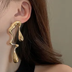 Orecchini a goccia dorati irregolari su modella, gioielli di design dallo stile audace.