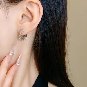 Detail view of elegant silver twisted textured hoop earrings worn on Asian model ear