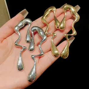 Dettaglio orecchini a goccia irregolari in metallo liquido in oro e argento