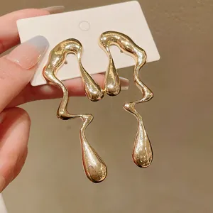 Dettaglio orecchini in metallo dorato irregolare con un design unico a goccia d'acqua