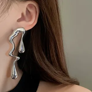 Dettaglio di orecchini irregolari in argento liquido indossati da una modella con stile