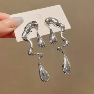 Primo piano di orecchini a goccia in metallo liquido irregolare con finitura argento
