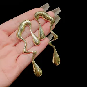 Vista dettagliata di orecchini a goccia dorati irregolari con design metallico ondulato