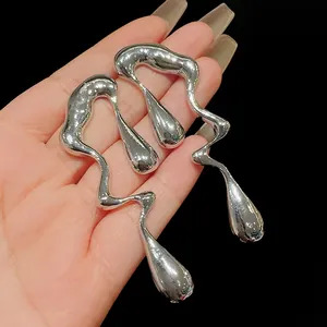 Dettaglio degli orecchini in argento a goccia di metallo liquido dalla forma irregolare.