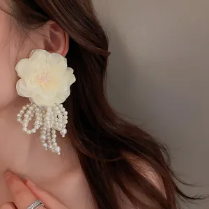 Detailansicht eleganter cremefarbener Blumenohrringe mit langen weißen Perlenquasten.