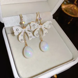Nahaufnahme von eleganten Schleifenohrringen mit irisierenden Perlen in einer Box