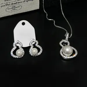 Elegant silver gourd jewelry set with sparkling zircons and white pearls on black background