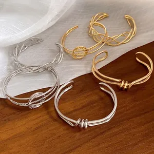 Collezione di bracciali a polsino intrecciati e annodati in finitura oro e argento