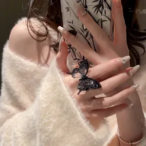 Close-up of a delicate black butterfly open ring on a model's finger with fuzzy sweater