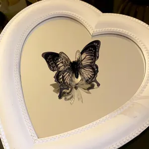 Detail shot of an elegant black 3D butterfly open ring displayed on a heart mirror