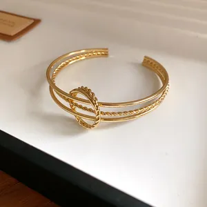 Dettaglio ravvicinato di un bracciale dorato a torsione irregolare con anello centrale