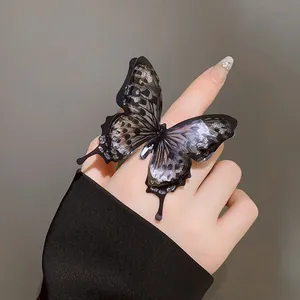Macro view of a stylish black butterfly open ring with silver glitter on index finger