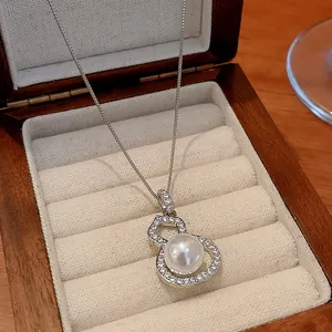 Detailed view of silver gourd pendant necklace with pavé zircons and white pearl