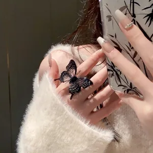 Detailed macro view of an intricate black butterfly open ring on a model's finger
