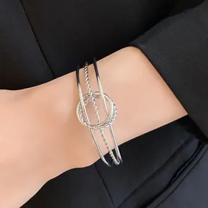 Dettaglio di un bracciale rigido in argento ritorto irregolare indossato sul polso femminile