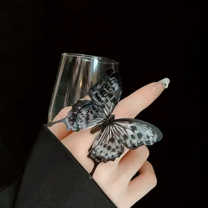 Detailed view of an elegant black butterfly adjustable ring with glitter on a finger