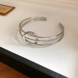 Vista dettagliata di un bracciale rigido aperto minimalista in argento intrecciato