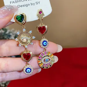 Detail von asymmetrischen Zirkon-Herzohrringen mit bunten Evil-Eye- und Hamsa-Anhängern.
