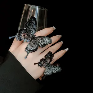Macro detail of elegant black butterfly open rings with glitter accents on a hand