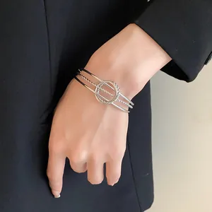 Primo piano di un bracciale rigido aperto a più strati in argento minimalista al polso